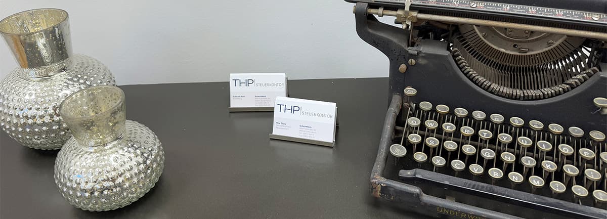 Visitenkarten von THP Steuerkontor neben einer alten Schreibmaschine